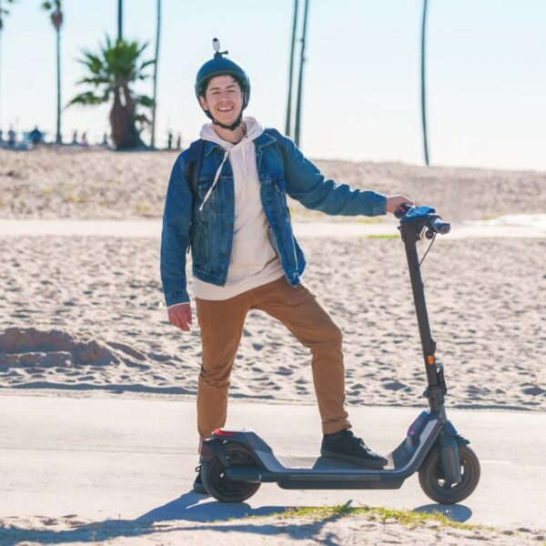 Segway Ninebot P65 trottinette électrique une personne près de la plage avec un casque sur la tête et un caméra dessus