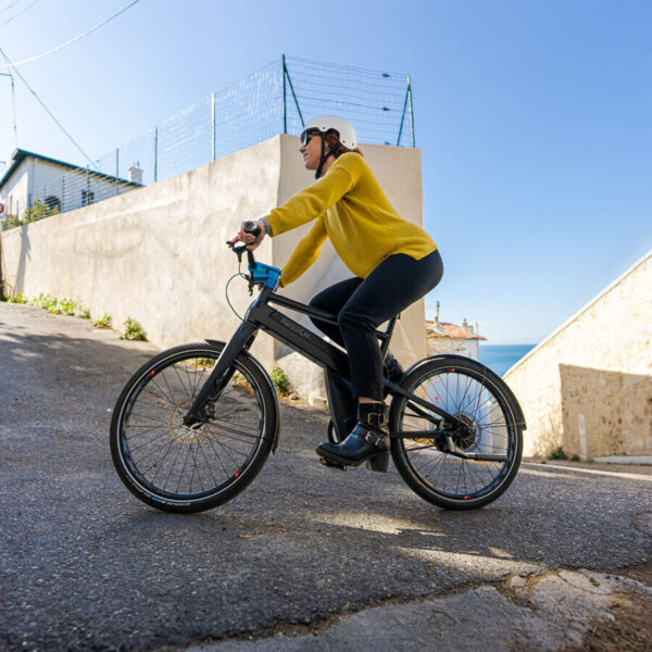 un vélo électrique IWEECH 24 S avec une femme monte une côte sans effort et avec le sourire