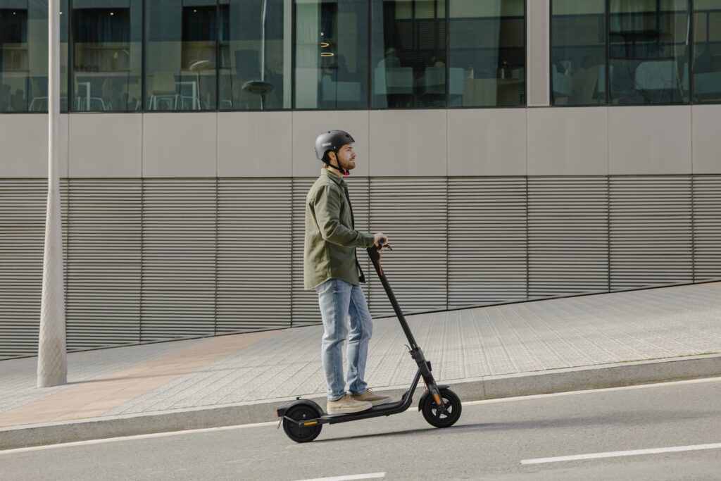 Un homme avec un casque sur la tête se rend à son travail avec sa trottinette électrique utilitaire