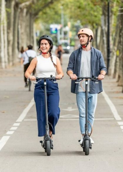 un couple avec leurs casque chacun sur une trottinette de la marque Ninebot Seegway