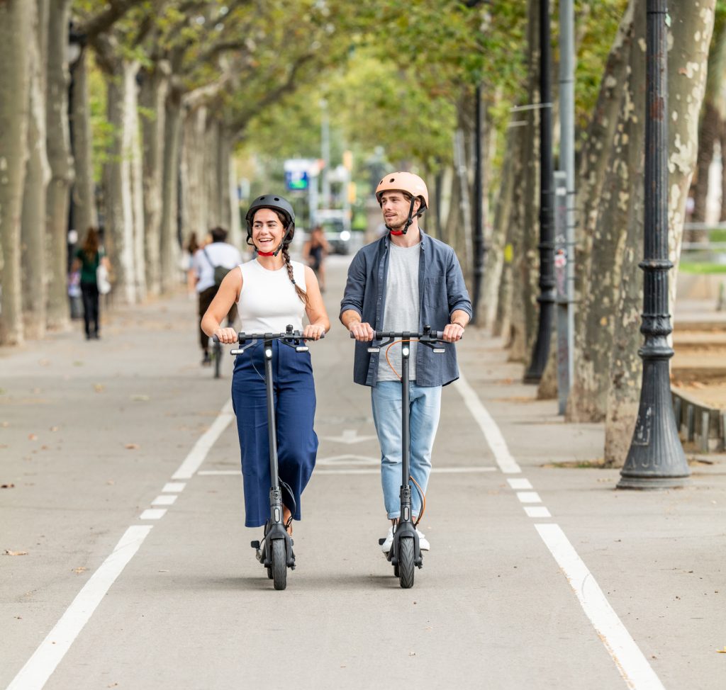 un couple avec leurs casque chacun sur une trottinette de la marque Ninebot Seegway
