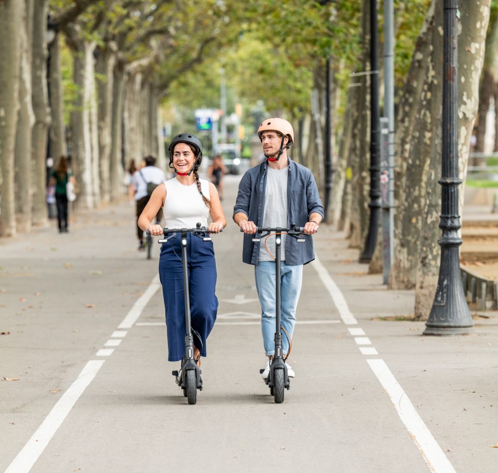 un couple avec leurs casque chacun sur une trottinette de la marque Ninebot Seegway