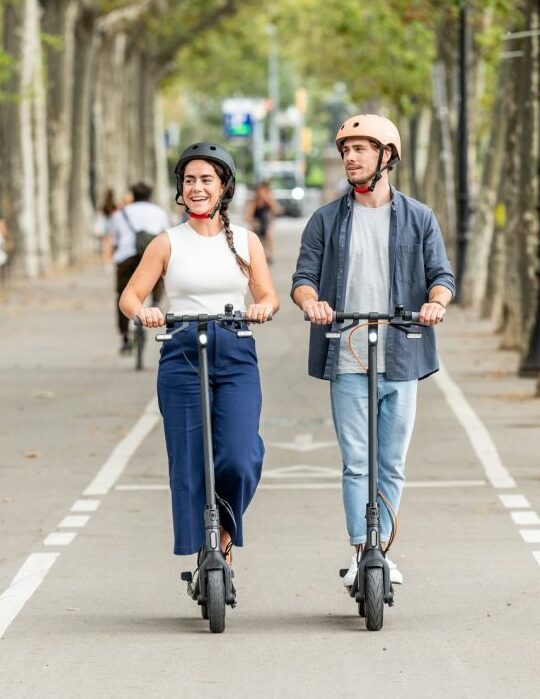 un couple avec leurs casque chacun sur une trottinette de la marque Ninebot Seegway